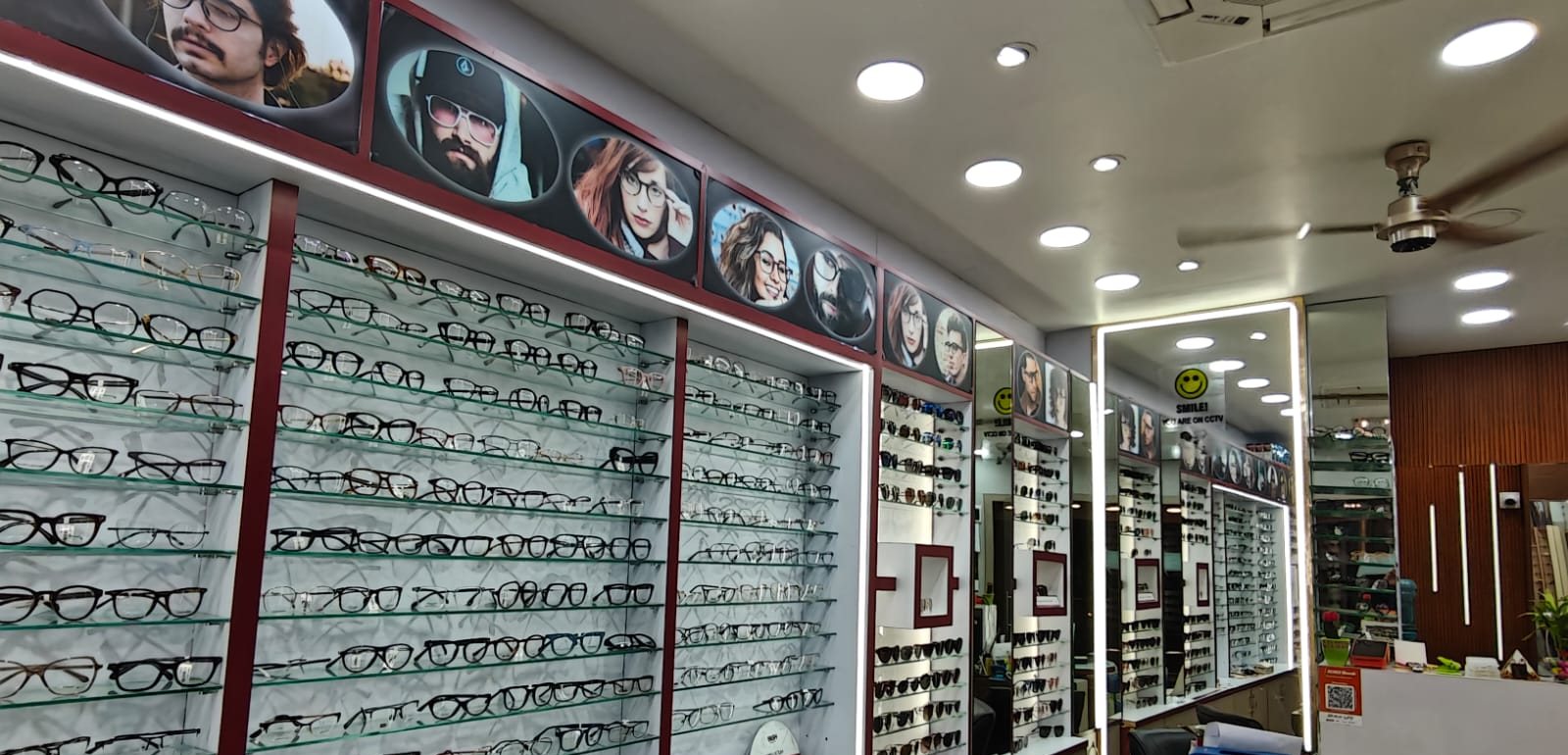 Backlit glass shelves of optical frames running the length of the store